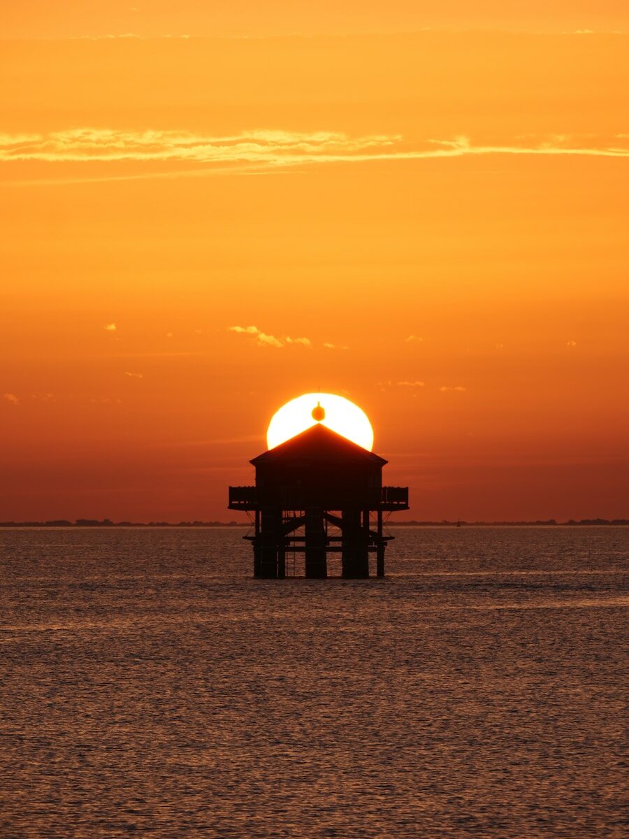 Silhouette of a lighthouse at sunset over the ocean.